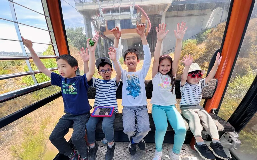 5 kids with hands up on gondola.Christine Shaw 1